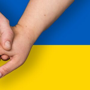 Ukrainan lippu ja sen päällä miehen, naisen ja lapsen käsi koskevat toisiaan.
